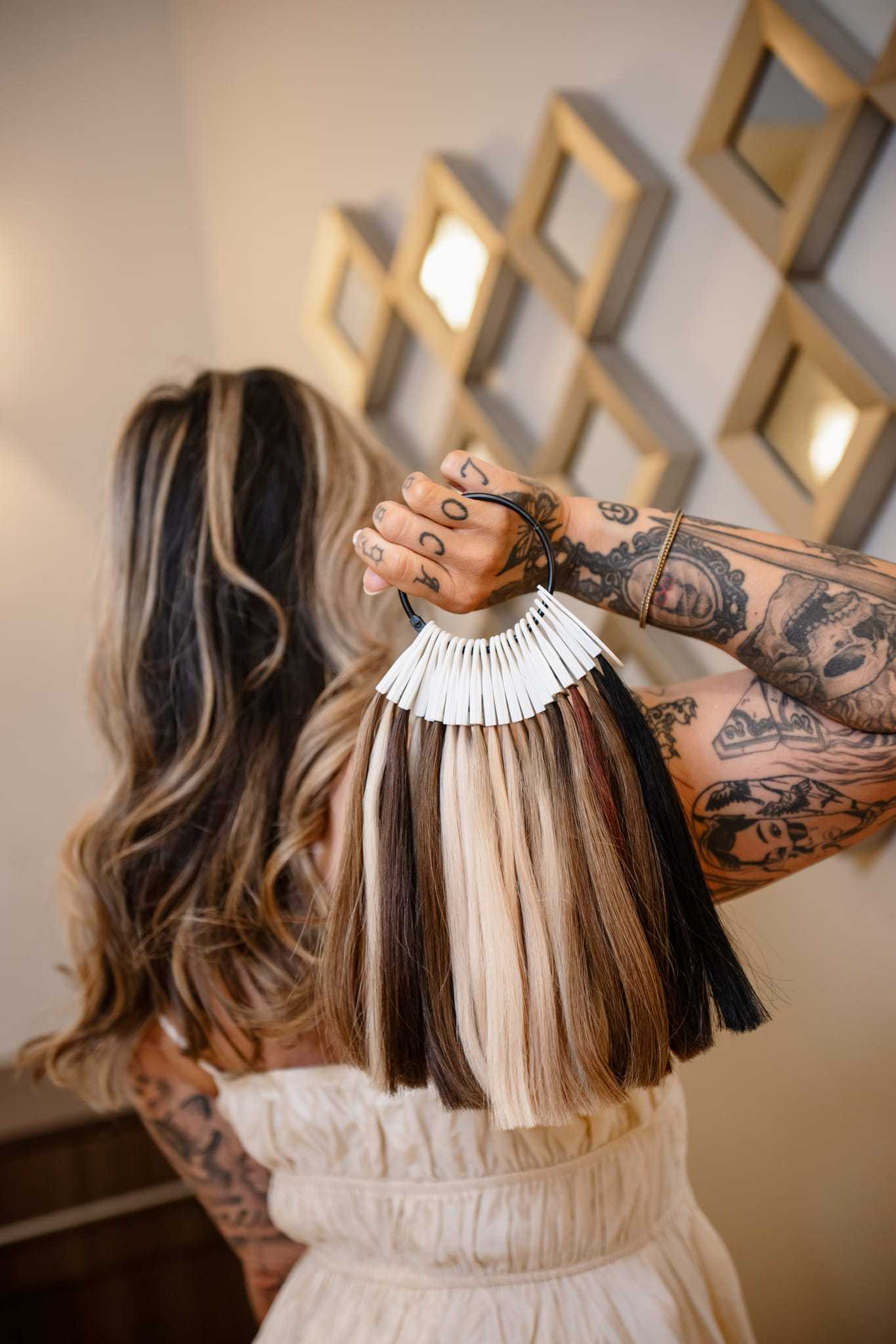 Woman with tattooed arms holding hair color samples.